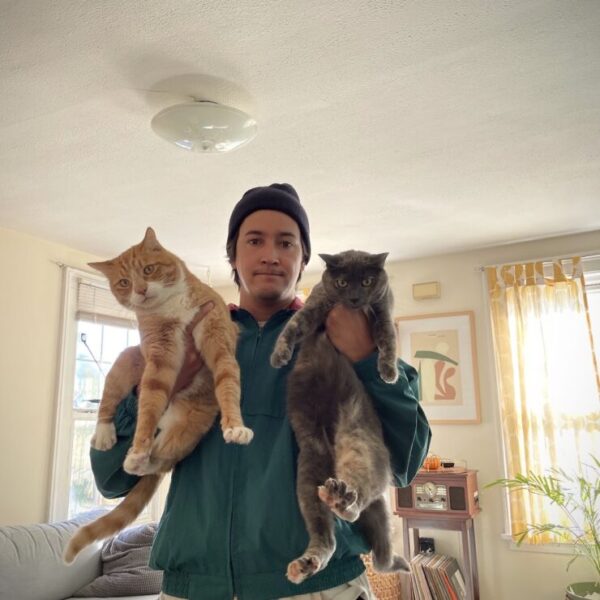 Photo of Miles Hanson holding a cat in each hand