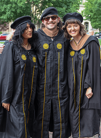 Three students dressed in graduation regalia