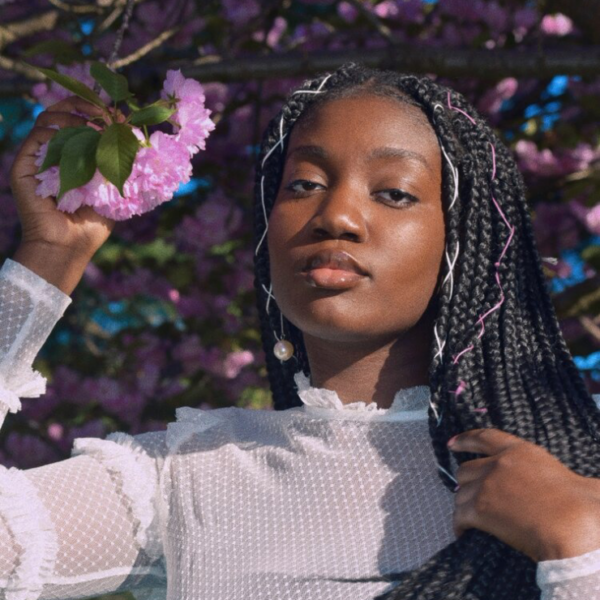 Headshot of Abi Diallo in front of tree with pink flowers