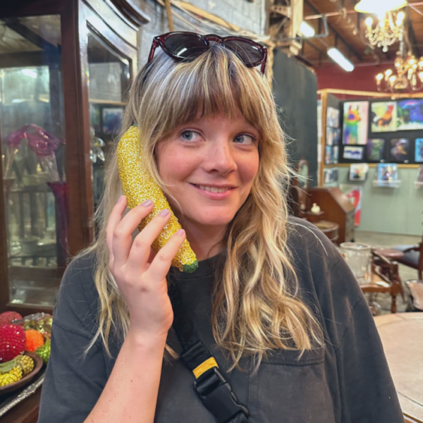 Photo of Allison Fitzgerald holding a glass figure shaped like corn up to her ear like a phone