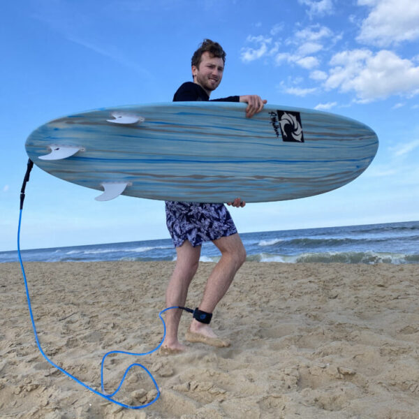 Photo of Nate Villaire with a surfboard on the beach