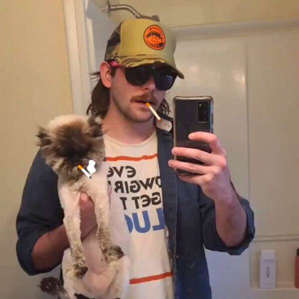 Photo of Travis Fairman taking a selfie in a mirror holding a cat