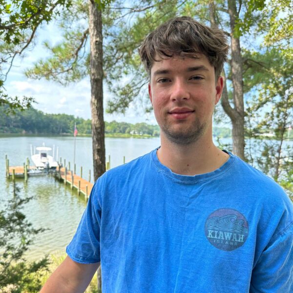 Photo of Luke Strother with a lake, dock, and boat behind him