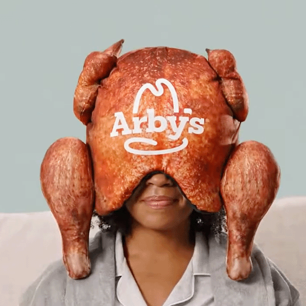 A screengrab of a woman with a fake prepared turkey on her head