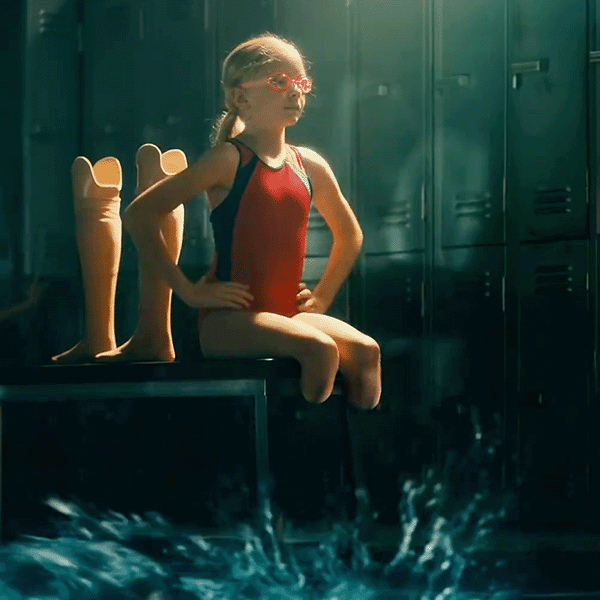 A screengrab of the Super Bowl commercial Toyota did telling Jessica Long's story—a little girl sits on a bench in a locker room with her prosthetic legs behind her and water splashing at her feet
