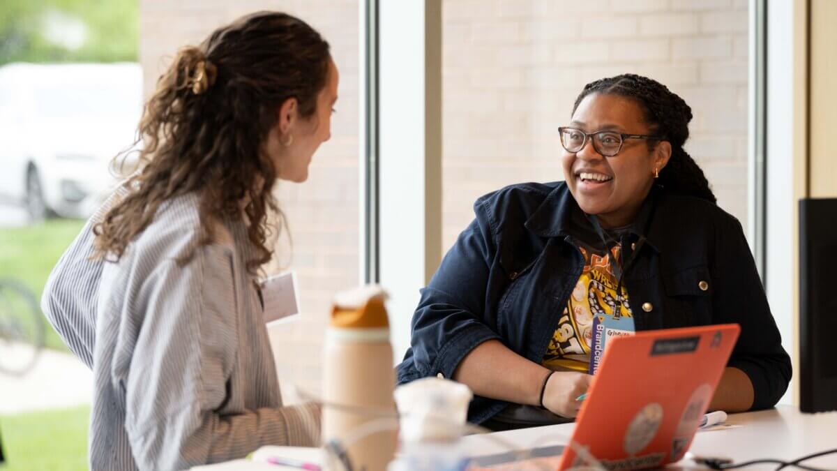 student and recruiter talking in the brandcenter basement with sunlight and windows behind them