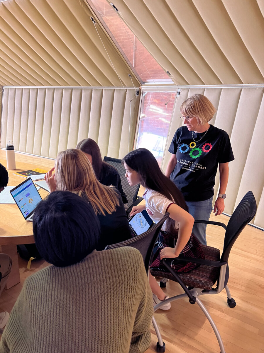 a group of students leaning over a table working on their project