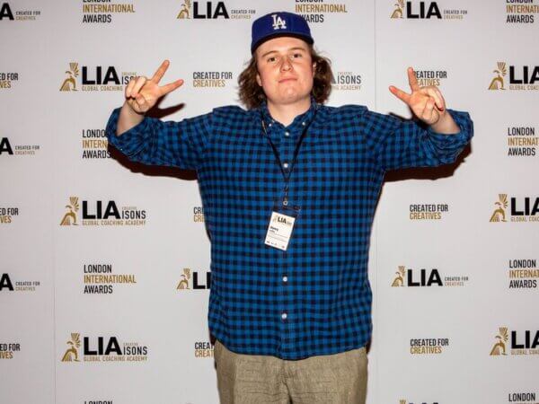 henry in front of a step and repeat holding hands in two peace signs