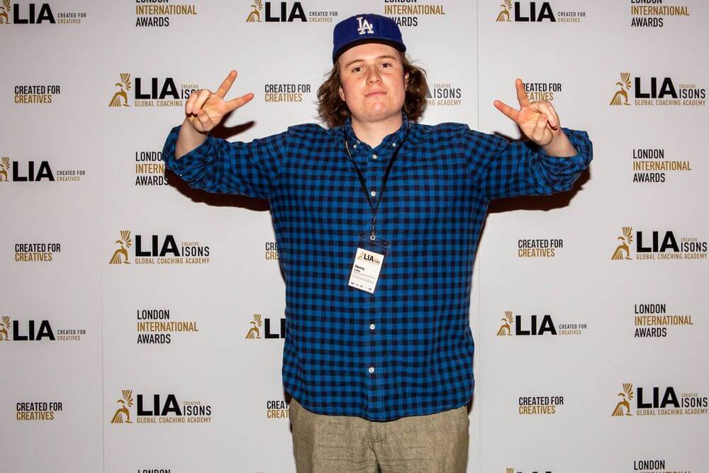 henry in front of a step and repeat holding hands in two peace signs