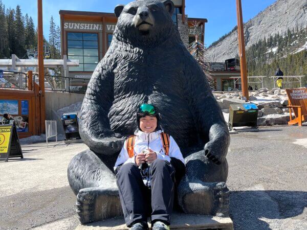 chen in snow gear in front of a bear statue